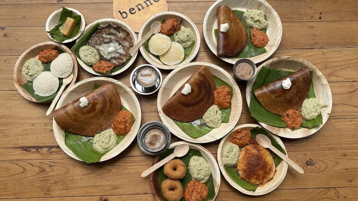 Benne dosa, idli, vada, and filter coffee spread on banana-leaf plates with a benne sign