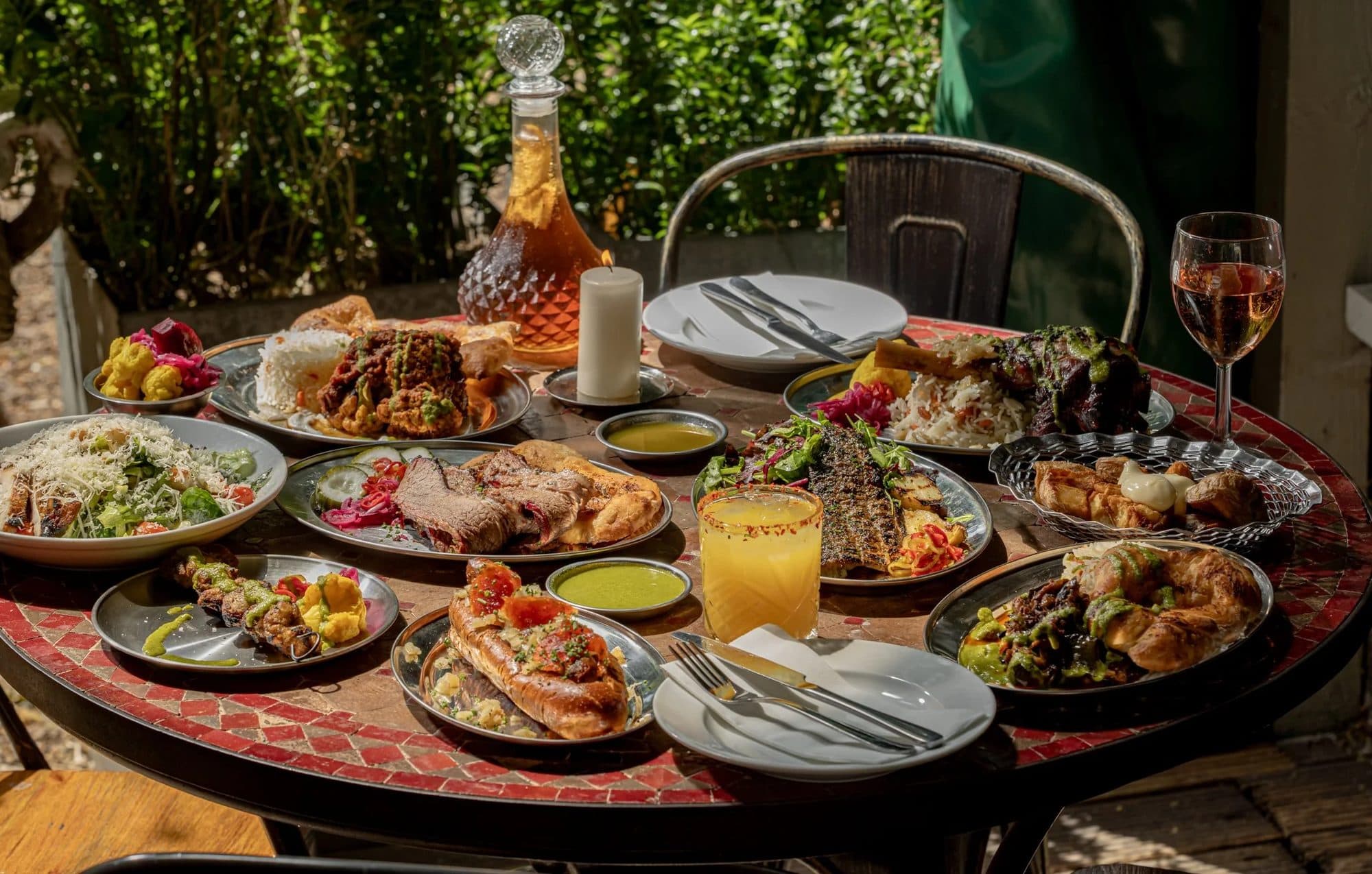 Sliced smoked brisket with naan, pickles, and an outdoor Cue Point feast spread