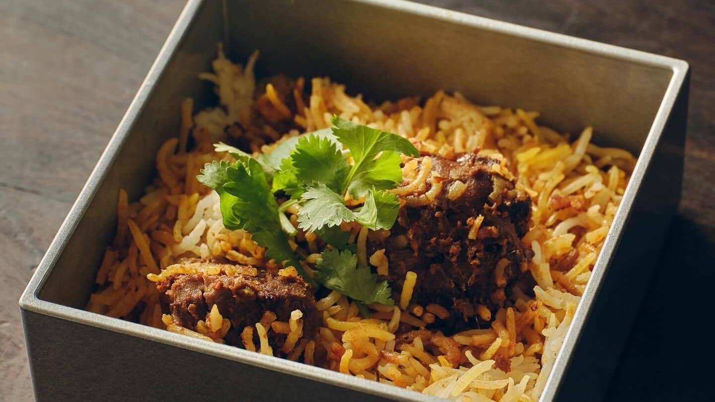 Biryani with long-grain rice and spiced meat in a square grey vessel, garnished with cilantro, from Biriyani Osawa