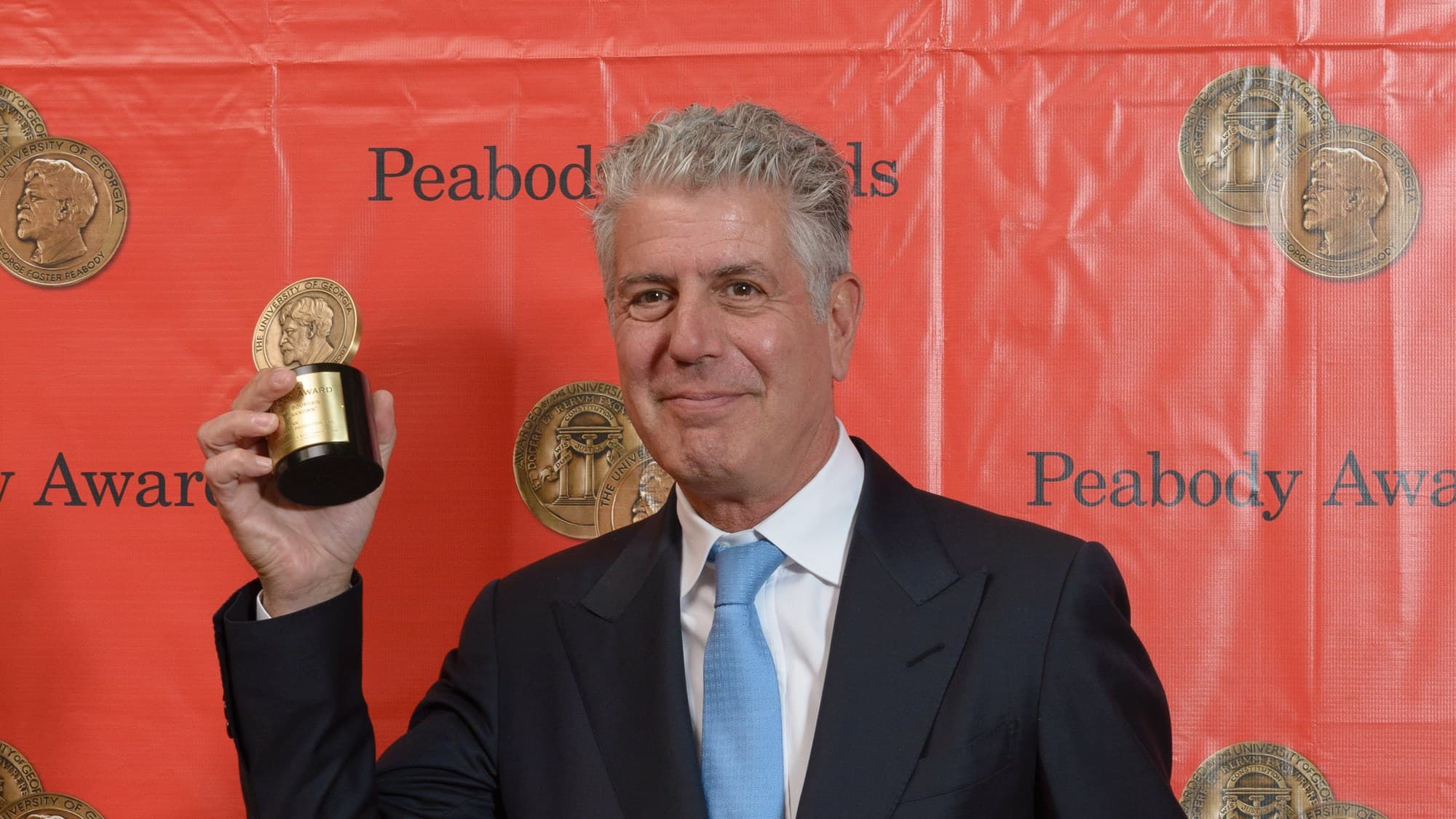 Anthony Bourdain smiling toward the camera at the 2014 Peabody Awards