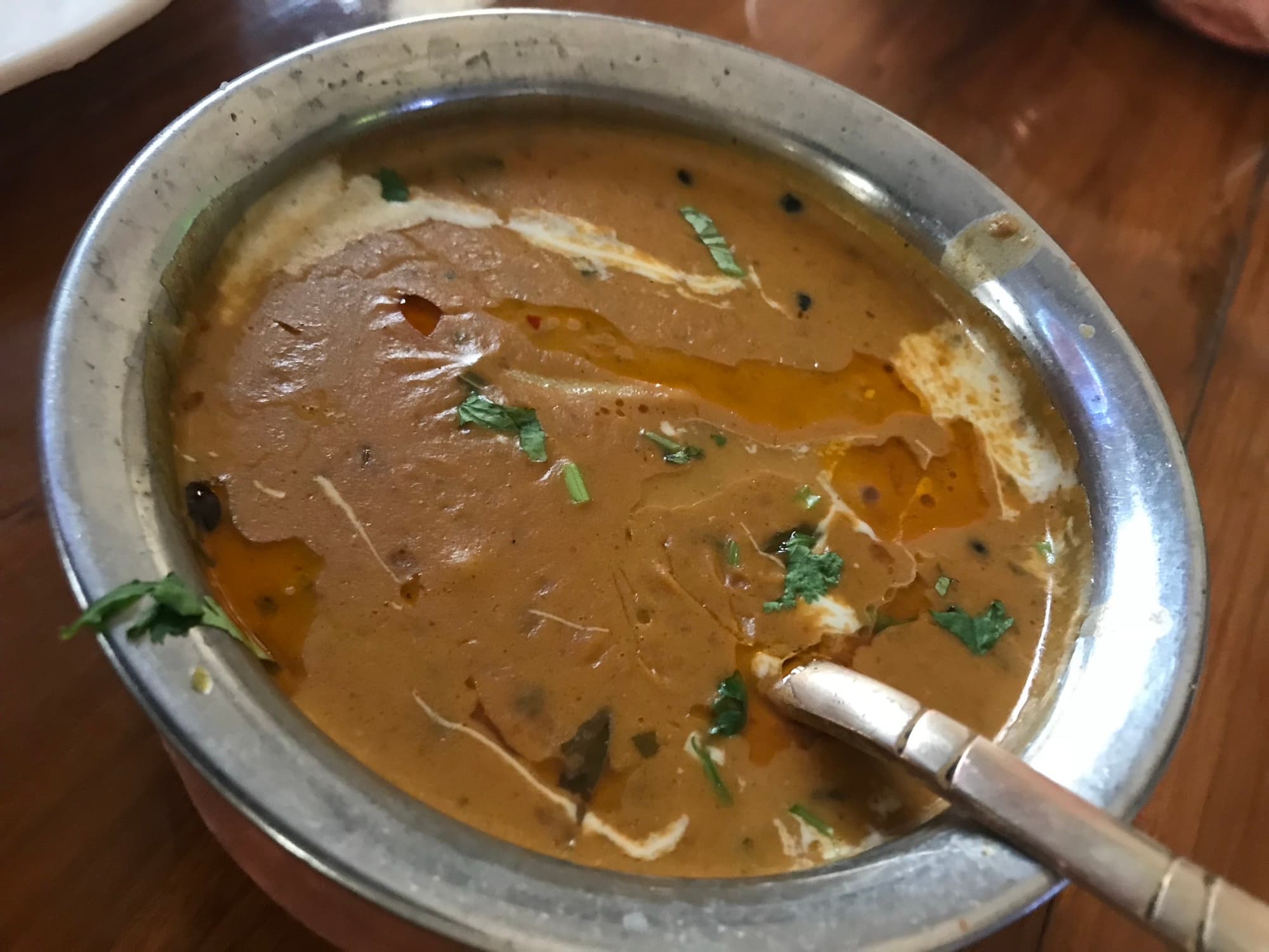 Creamy dal makhani in a steel bowl with cream swirl, ghee, and cilantro