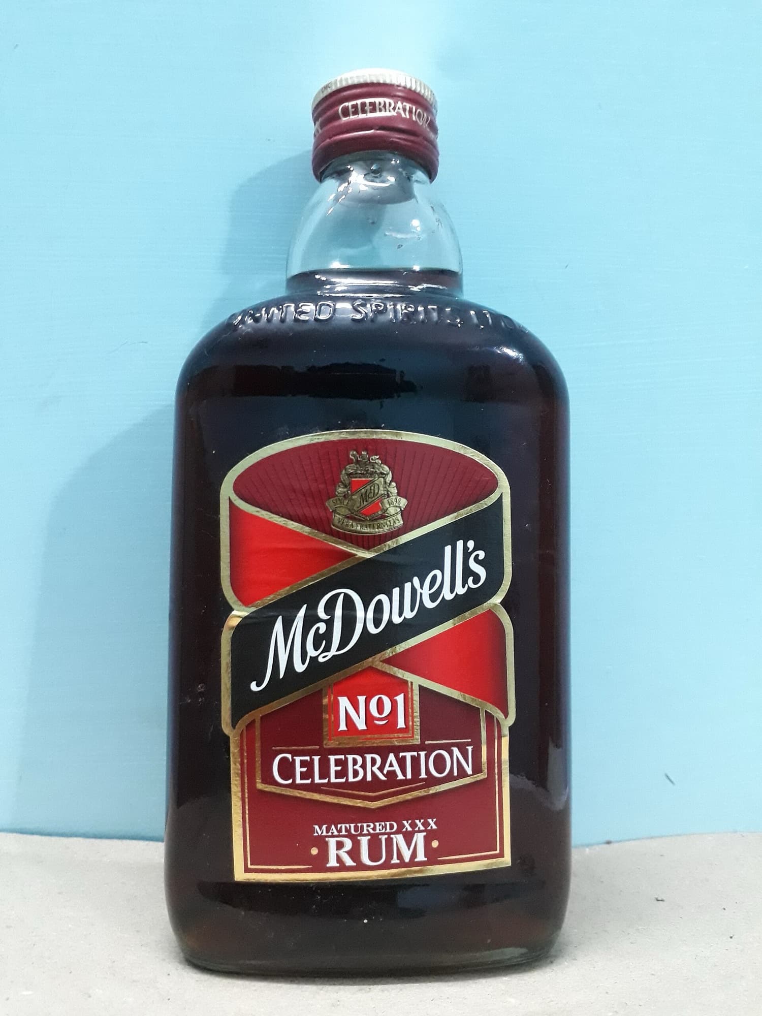 Upright bottle of McDowell’s No. 1 Celebration rum with red and gold label