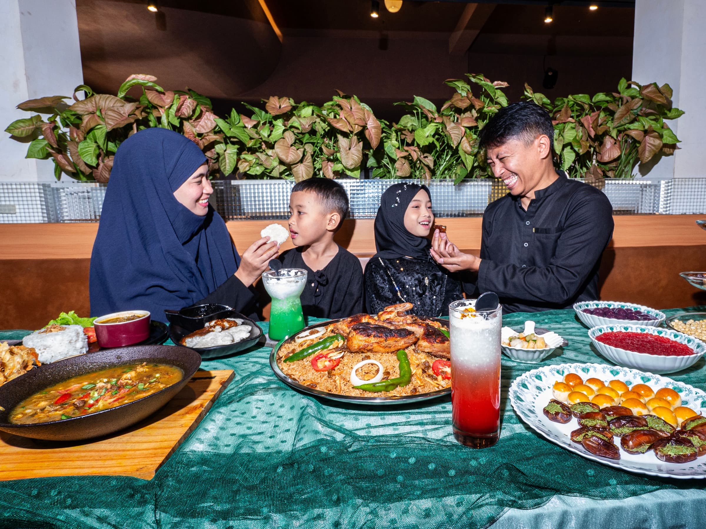 Muslim family sharing rice, dates, sweets, and other dishes at a festive meal