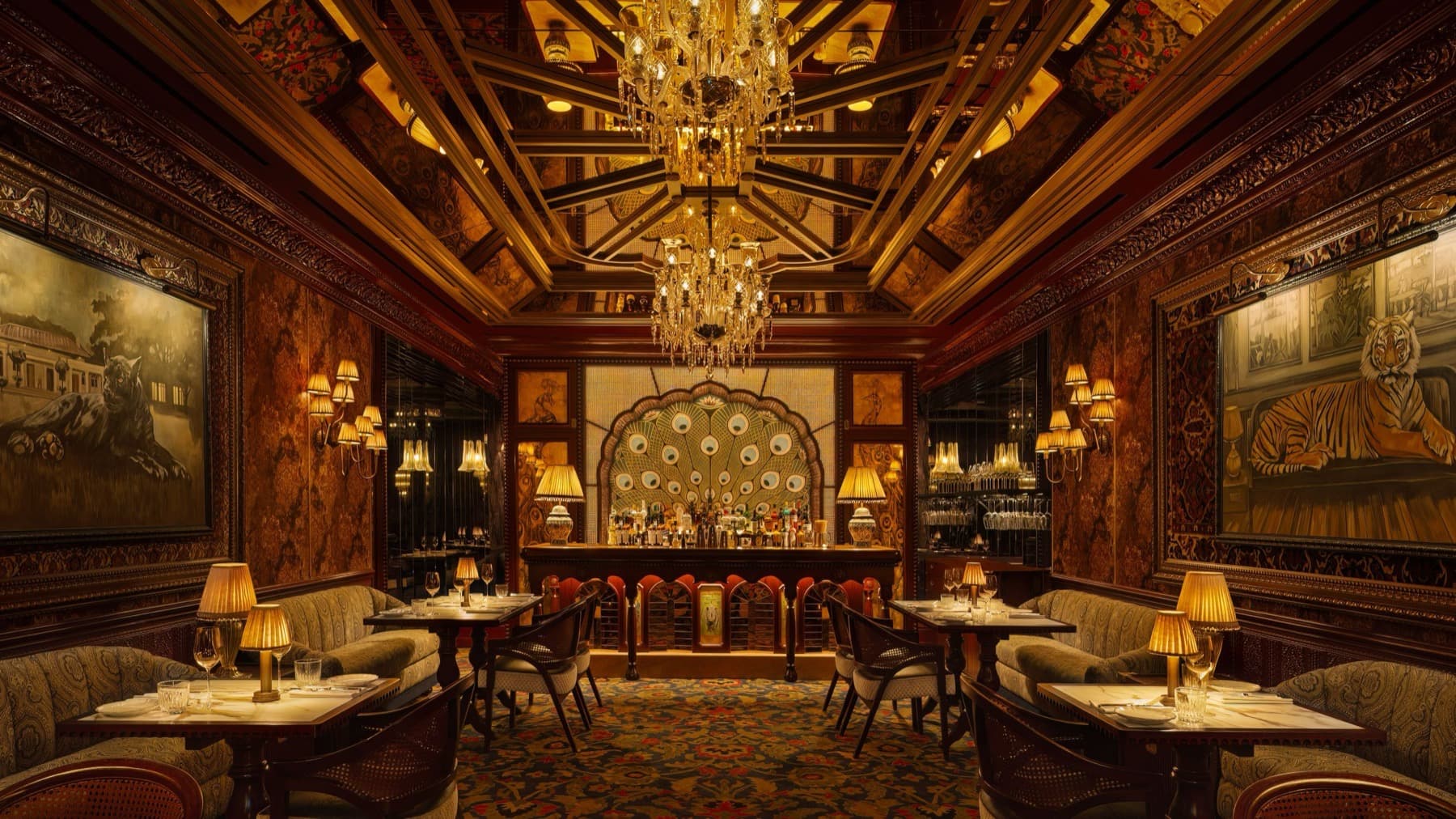 Gymkhana Dubai dining room with peacock-tail bar, crystal chandeliers, and club chairs