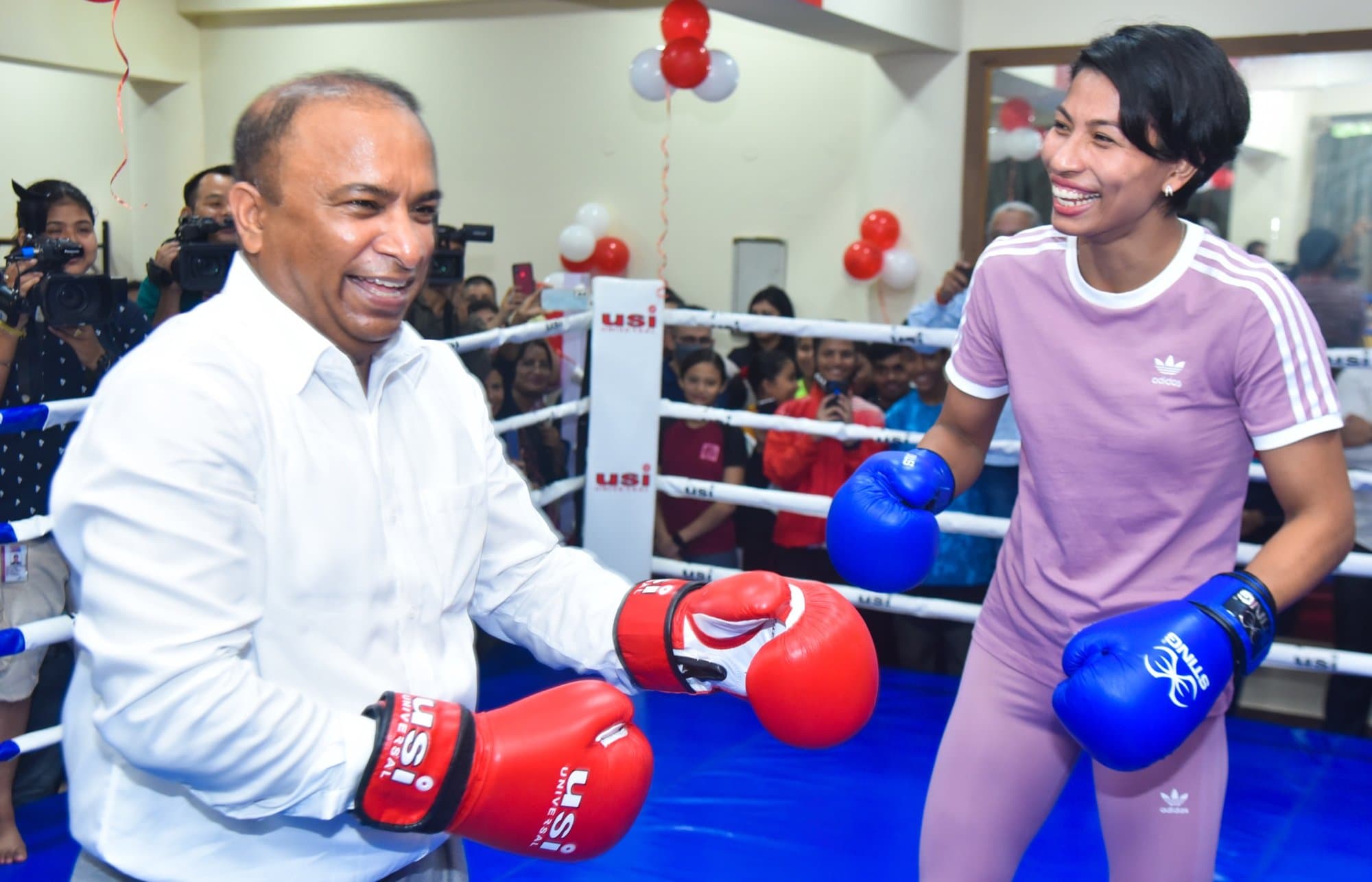Lovlina Borgohain smiling in a boxing ring in pink Adidas kit with blue gloves