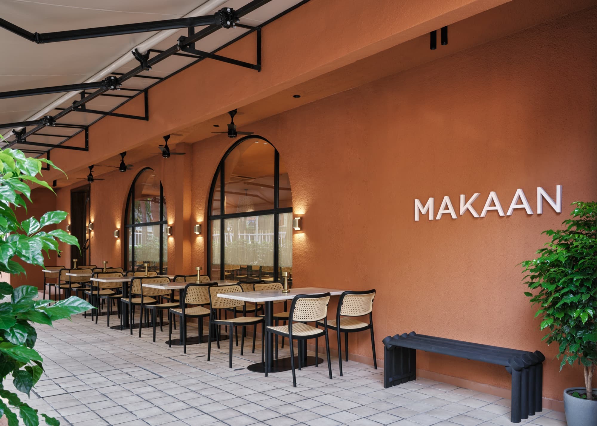 The terracotta terrace at Makaan in Juhu, with the name on the wall and cane chairs under arched windows