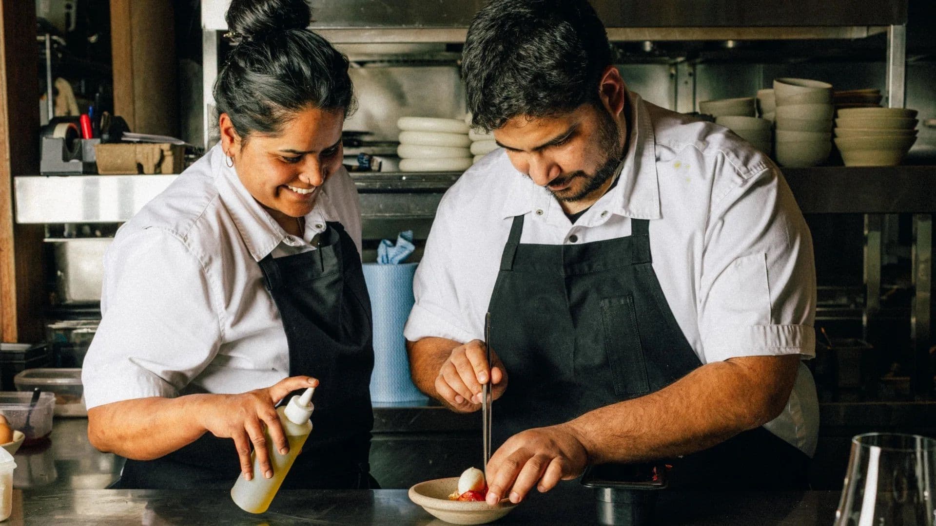 Chefs Saavni Krishnan and Aditya Suresh plating a dish together in the Saadi kitchen