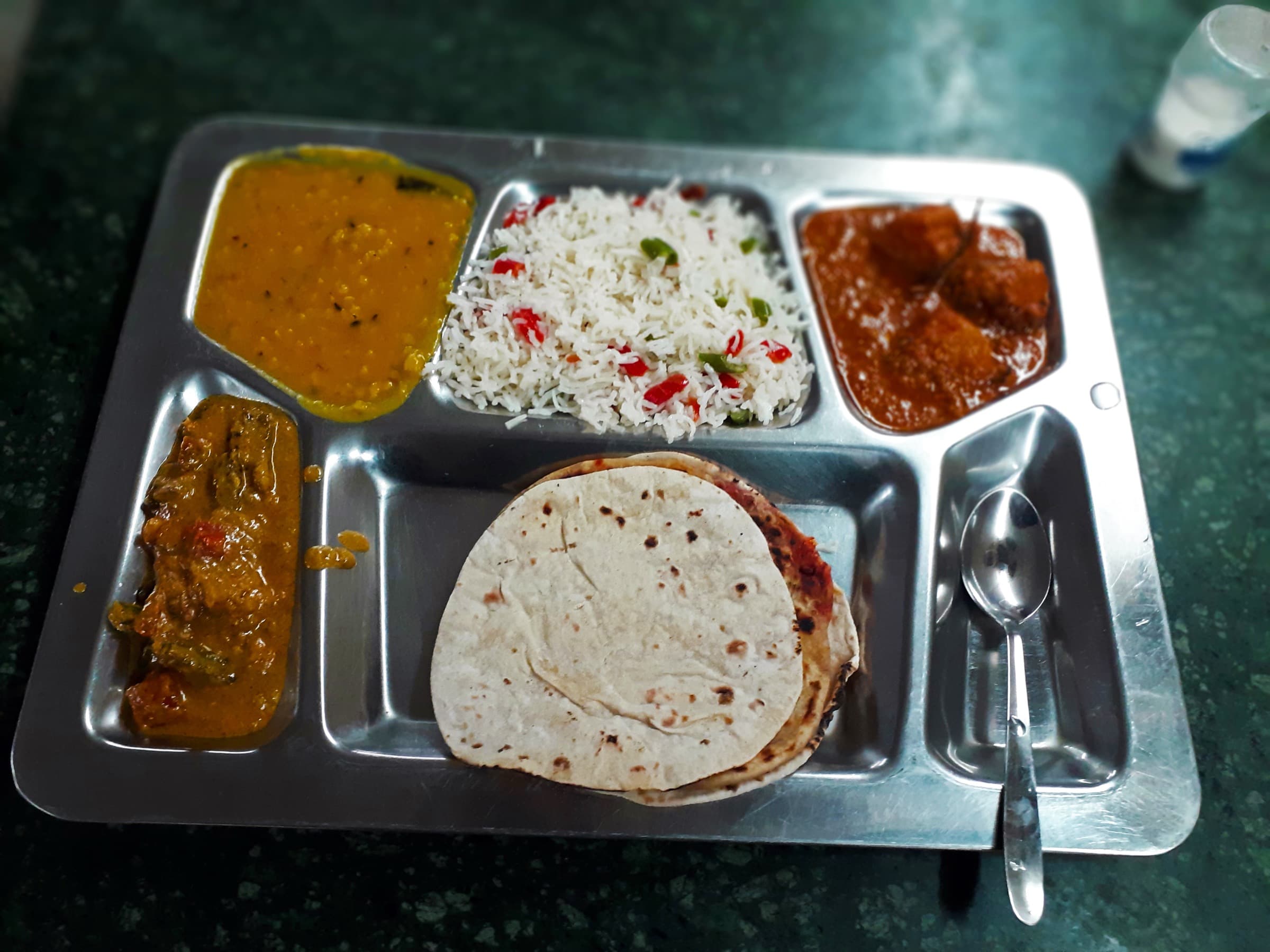 North Indian vegetarian thali with dal, rice, paneer, sabzi, and roti in a steel tray