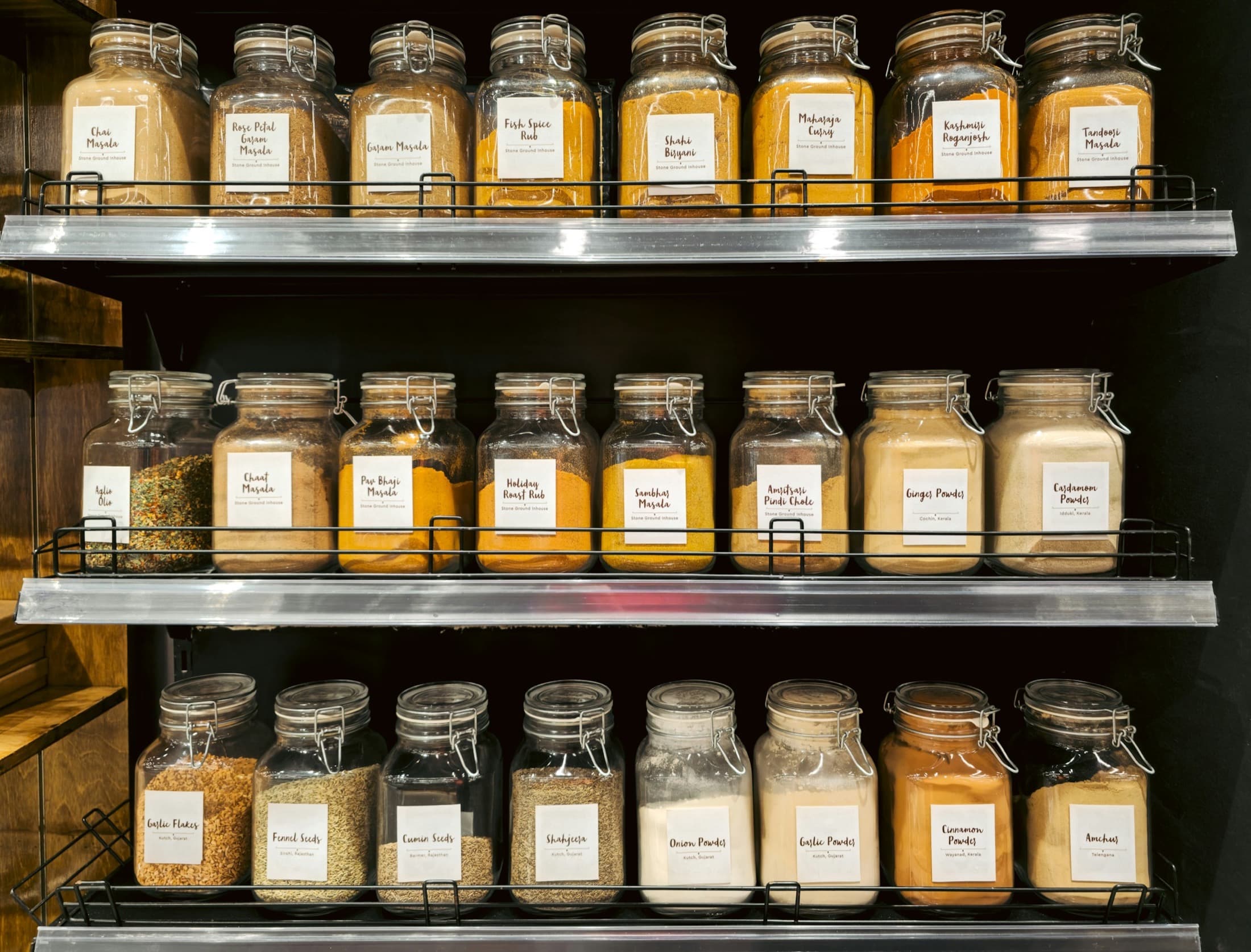 Glass jars of turmeric, chili, and other Indian spices lined on grocery shelves
