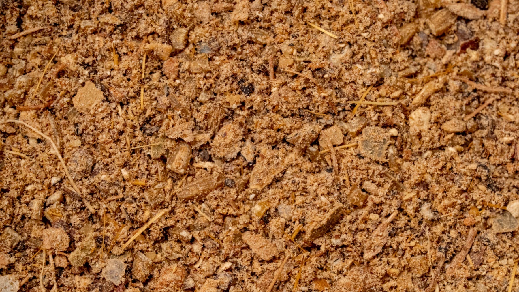 Close-up of coarse garam masala showing mixed grains, bark flecks, and dark spice particles