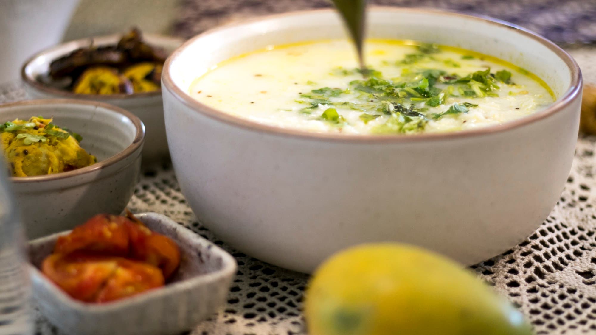 Bowl of Odia pakhala rice with cilantro, surrounded by small side dishes
