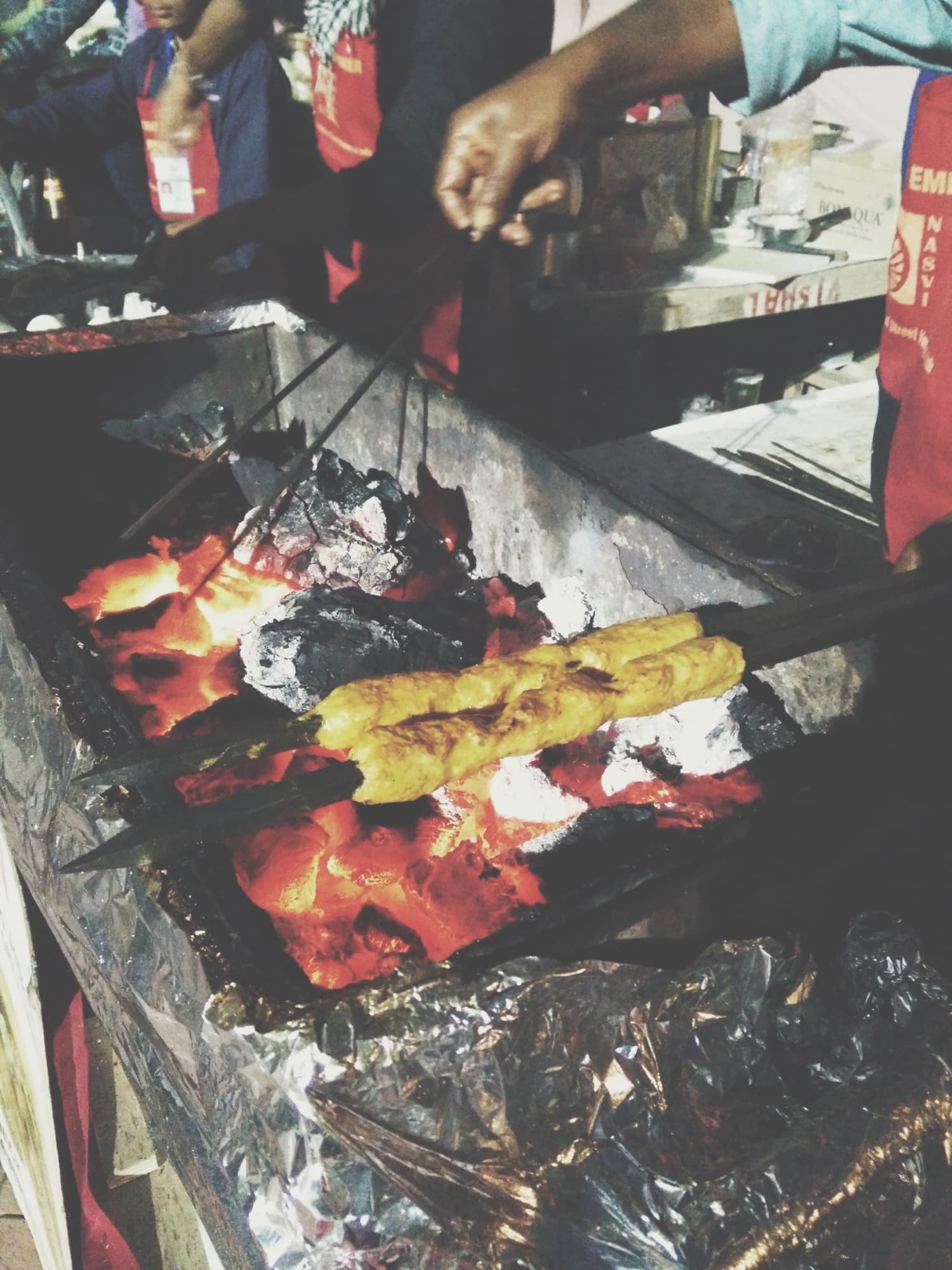 Seekh kebabs cooking over charcoal on a metal grill